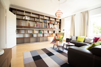 Das Wohnzimmer im Gunther49 ist mit einem Designerregal aus lackiertem Metall in Einzelanfertigung und einem in den Sitzflächen elektrisch verstellbaren italienischen Designerecksofa aus braunem Leder der Marke CALIA ITALIA ausgestattet.